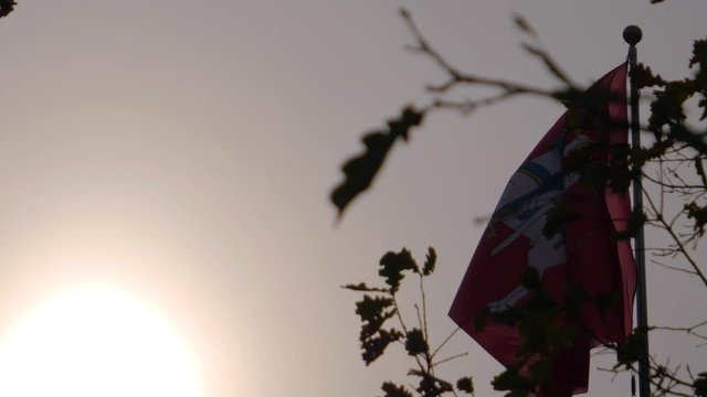 Looking up at the Vytis Coat of Arms on a flag unfurling in the wind in slow motion at Kaunas Castle, Lithuania