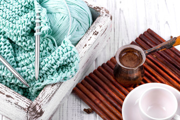Handmade knitting and cup of coffee on the white wooden table