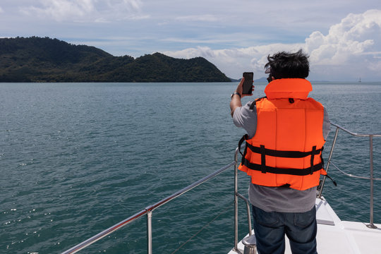 tourist take picture with mobile phone yacht cruise at Phuket, Thailand