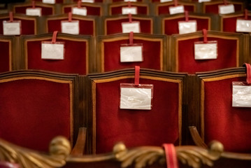Armchairs of an old theater of red cloth, with blank labels, for attendees.
