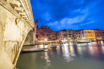 Rialto Bridge at night with city restaurants along grand canal, Venice, Italy