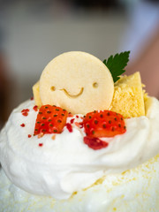 Kakigori, Japanese shaved ice dessert flavored with condensed milk, topping with smiled cookey, strawberry and whipping cream on table in restaurant