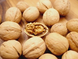 Photo of several walnuts in shell and one open walnut between them.