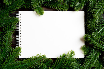 Top view of notebook decorated with a frame made of fir tree on wooden background. New Year time concept