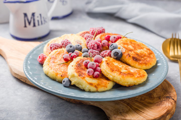 Naklejka na ściany i meble Breakfast with cheesecake, fresh berries . Cottage cheese pancakes or curd fritters. Russian syrniki or sirniki