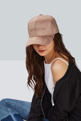 Cropped upward shot of a dark-haired girl, wearing beige velvet baseball cap with embroidery...