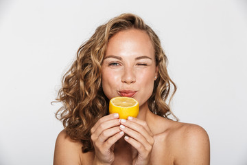 Image of attractive half-naked woman winking and eating lemon