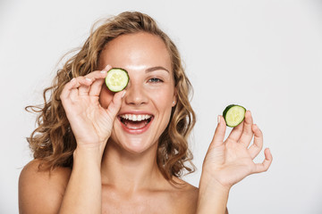 Image of happy half-naked woman smiling and pieces of cucumber