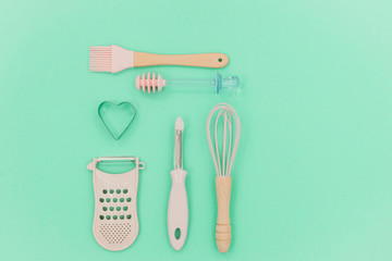 Flatlay  pink kitchen utensils on neo mint background. Greater, whisk and iron cooking form. Top...