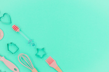 Flatlay  pink kitchen utensils on neo mint background. Greater, whisk and iron cooking form. Top horizontal view copyspace love cookong concept