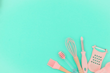 Flatlay  pink kitchen utensils on neo mint background. Greater, whisk and iron cooking form. Top...