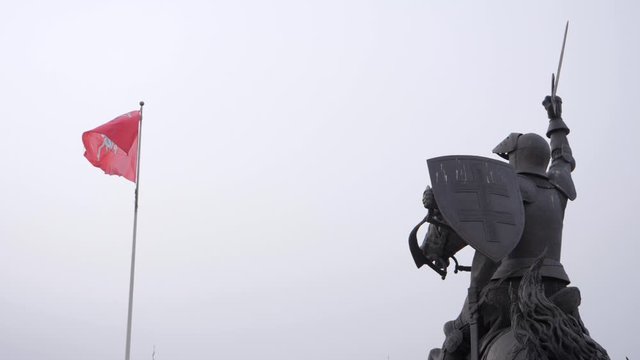 Looking up at the Vytis coat of arms on a flag next to the Freedom Warrior statue in Kaunas castle, Lithuania