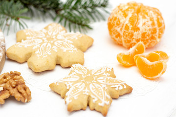 Christmas gingerbread snowflakes lie on a white wooden background. tangerine, walnut and spruce natural on the background