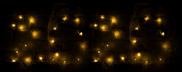 Garland lights on the dark brick wall. Date 2020 New Year