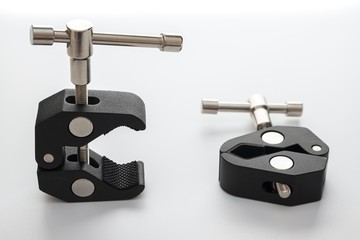 Two Clip for DSLR or mirrorless Camera. Photo acsessories both 1 4 and 3 8 inch screw. Articulating Magic Friction Arm Small Super Clamp Crab Pliers. White background with texture. Not isolated.