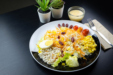 Vegetable salad on a black and white plate On a black wooden table. For weight control people. 45 degree angle.