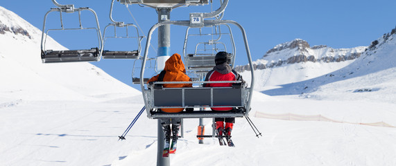 Two skiers on chair-lift and snow ski slope - obrazy, fototapety, plakaty
