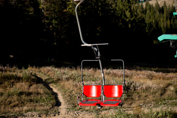 Close up of red chairlift going over trees in summer on Mountain. Carpathian national park