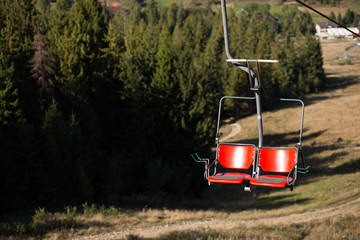 Close up of red chairlift going over trees in summer on Mountain. Carpathian national park