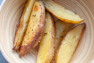 baked slices of potato in wooden bowl