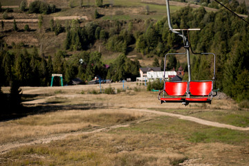 Close up of red chairlift going over trees in summer on Mountain. Carpathian national park