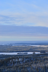Fototapeta na wymiar Finnisht winter, Kuusamo. Landscape from Konttainen. Fading daylight, colorful horizon and frozen lakes. Mist descends over the forested hills.
