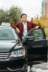 Taxi driver looking away beside open car door