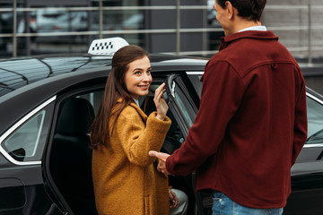 Taxi driver opening auto door for smiling woman