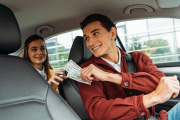 Smiling passenger paying off with taxi driver