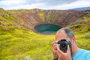 Fototapeta premium Portrait of a photographer covering her face with the camera taking shots of Iceland Crater