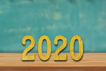 Happy New Year 2020 written in gold letters on a wooden table.