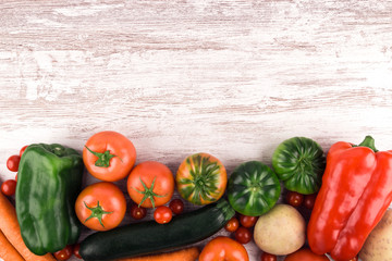 Top view of fresh raw vegetables placed to leave a space for text or an image at the top of the photo. Rustic white wood background. Copy space. Healthy food. Natural products. Nature and well-being