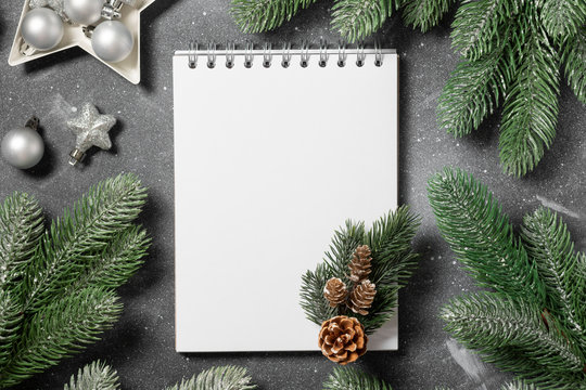 Christmas or New year holiday background with open blank Notepad, fir branches and Christmas traditional decorations. Checklist or letter to Santa. Top view with copy space