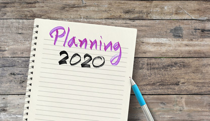 Planning 2020 Handwriting on notepad over wood table - business concept