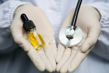 CBD hemp oil bottles and medical stethoscope In the hands of researchers or medical teams wearing white gloves. The concept of alternative medicine The invention of natural herbs as medicines.