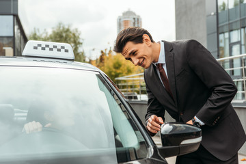 Fototapeta na wymiar Handsome businessman pointing on something to taxi driver on street