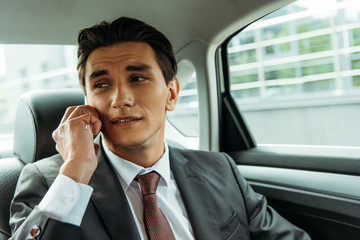 Handsome businessman talking on smartphone in taxi