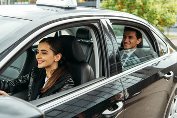 Fototapeta na wymiar Smiling female taxi driver and businessman in car