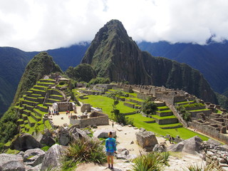 A woman tourist standing in front of the ancient Inca town of Machu Picchu with Huayna Picchu...