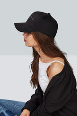 Cropped side photo of a girl, wearing black velvet baseball cap with embroidery lettering 