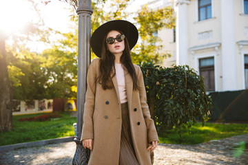 Fototapeta premium Portrait of adorable woman in sunglasses walking in green garden outdoors