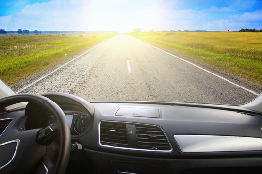 View from the windshield of a car driving along a sunset road