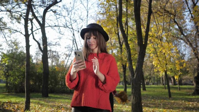 beautiful girls have fun in the autumn park throw leaves and take a selfie on a cell phone in the fall season