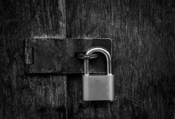 Fototapeta premium Locked padlock with chain at gray wooden door. black and white.