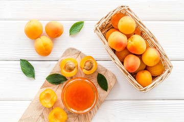 Friut background with apricot jam on white wooden background top view
