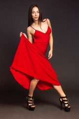 brunette on a dark background posing in a red dress