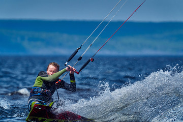Naklejka premium A male kiter slides on the surface of the water. Splashes of water fly apart. Close-up.