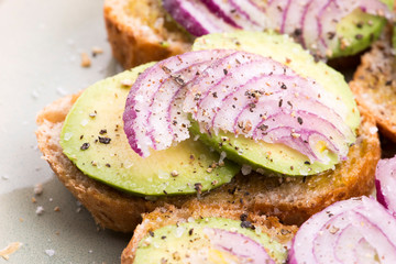 Sandwich with fresh avocado and onion on a plate