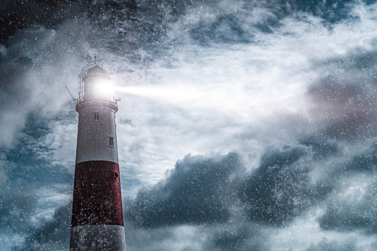 Large lighthouse with bright search light on a dark and stormy night