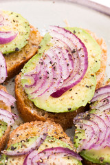 Sandwich with fresh avocado and onion on a plate